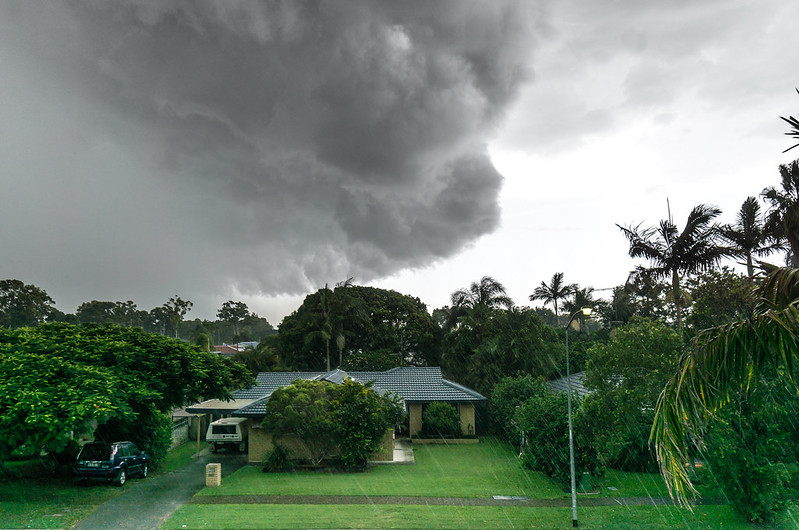 A thunderstorm darkens the sky over a house.