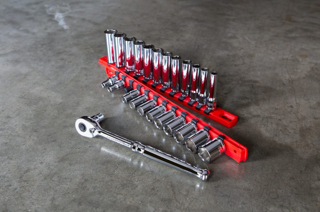 A silver ratchet and socket set sitting on a concrete floor